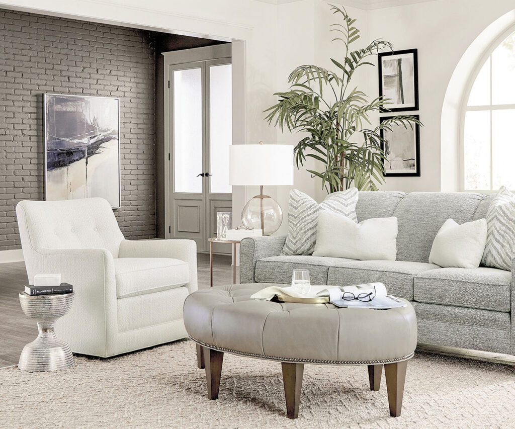 Light gray sofa and white swivel chair with tufted ottoman in airy living room