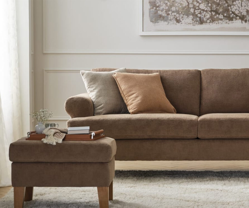 Brown upholstered sofa with ottoman, neutral pillows, and tray in cozy living room